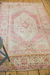 Distressed vintage Oushak rug with faded blush, ivory geometric patterns and secured fringe.