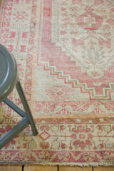 Faded blush and ivory geometric border detail of a vintage distressed Oushak rug.
