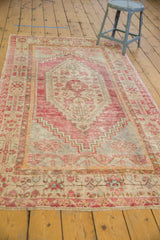 Distressed Oushak rug end with secured fringe, showing faded blush and beige tones.