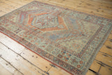 Distressed Oushak rug showing faded terracotta and slate blue geometric patterns with wear to knot heads.