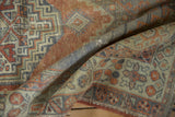 Detail of folded vintage distressed Oushak rug pile, showing terracotta, blue-grey, and beige abrashes.