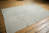 Soft ivory, pale gray distressed Oushak rug with subtle motif and varied texture.