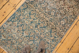 Distressed vintage Malayer runner with faded blue and ivory Herati pattern, beneath spotted shoes.