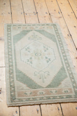 Distressed Oushak rug showing its evenly worn ivory pile and serrated celadon green contour.