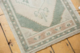 Secured fringe and celadon green border on a distressed vintage Oushak rug end.