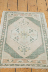 Distressed Oushak rug end border with serrated patterns in celadon green, ivory, and pale beige.