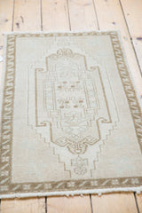 Textured ivory and pale bronze stepped patterns with seafoam accents on a vintage Oushak rug.