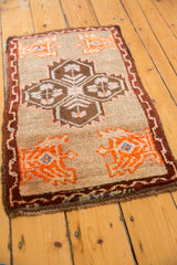 Close-up of tangerine germinating planter motif and chocolate vine border on vintage Oushak rug.