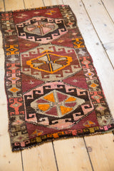 Playful Oushak runner featuring aubergine, blush, and tangerine geometric village patterns.