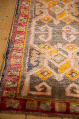 Detail of vintage Oushak rug pile with raspberry red border and scrolling rams horn motifs on oxidized silver.
