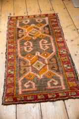 Corner of vintage Oushak rug, showing scrolling vinery on dark ground, thick pile, and red border.