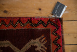 Thick pile corner of vintage Oushak rug with wine red field, zigzag border, and tag.