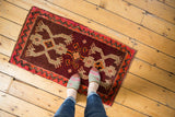 Vintage Oushak rug with wine red field, tan crab medallions, shown with feet for scale.
