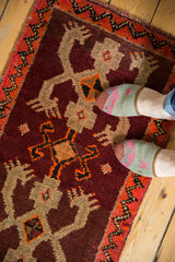 Vintage Oushak rug's thick pile, featuring wine red field, tan crab motifs, orange zigzag border.