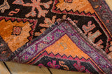 Folded vintage Oushak rug showing thick tangerine orange pile, dark geometric patterns, and secured edge.