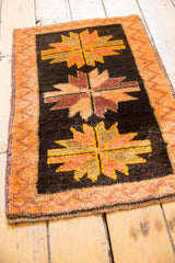 Vintage Oushak rug mat detail, featuring a floral medallion, tangerine zig-zag border, and secured end.
