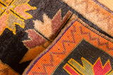 Vintage Oushak rug corner with tangerine zig-zag border and floral patterns on dark brown.