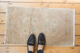 Distressed vintage Oushak rug corner, showing even wear and ivory fringe.