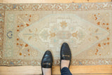 Distressed Oushak runner corner, showcasing detailed arabesque spandrel in ivory, terracotta, pale blue.