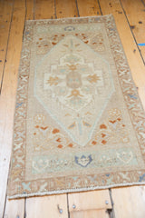 Vintage distressed Oushak runner with faded ivory, terracotta, and pale blue floral medallion.
