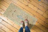 Vintage Oushak mat runner with ivory and sea green rectilinear medallion, feet for scale.