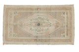 Distressed vintage Oushak rug mat with a muted medallion, floral patterns, and soft neutral colors.