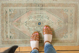 Faded central medallion and serrated field of a distressed Oushak rug in ivory, pale seafoam, and sand.