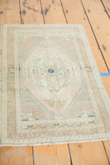 Distressed Oushak rug mat corner, with light fringe and faded floral-geometric border.