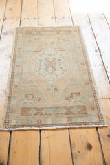 Soft fringed end of a distressed Oushak rug showing pale bronze and seafoam mint details.