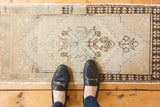 Distressed Oushak rug: central serrated medallion with ivory, seafoam, brown floral motifs, even wear.