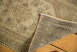 Folded corner of a Vintage Oushak rug showing its hand-knotted foundation and low pile in beige and ivory.