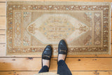 Oushak rug's central ivory medallion with distressed pile and pale seafoam, sand tones.
