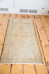 Distressed Oushak rug's central medallion and stepped field overlay in soft ivory and sand.