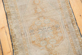 Worn texture of distressed Oushak rug, pale bronze design on ivory field with dark selvage.