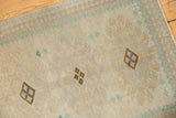 Distressed Oushak rug mat's side selvage, geometric motifs, and even pile wear in ivory, seafoam, chocolate.