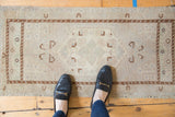 Distressed vintage Oushak rug showing worn beige pile, brown border, and soft seafoam accents.