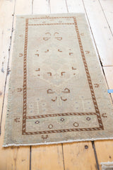 Vintage distressed Oushak rug corner showing worn beige pile and chocolate brown geometric border.