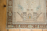 Distressed Oushak rug corner shows architectural border, plant motifs, even pile, and selvage.
