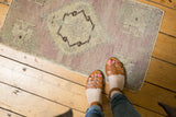 Pale mauve and ivory distressed Oushak rug mat showing worn pile and serrated medallion detail.