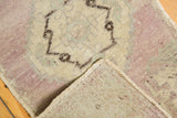 Oushak rug mat corner: distressed pale mauve, ivory pile, original selvage, and woven foundation.
