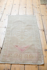 Vintage distressed Oushak rug corner, showing faint blush rose pattern and fringe.