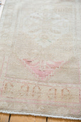 Faded blush rose border and ivory fringe on a distressed vintage Oushak rug's end.