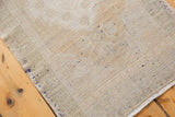 Distressed Oushak rug with worn ivory and beige pile, revealing faint dark foundation.