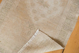 Distressed ivory beige Oushak rug detail: worn pile, fringe, and tightly woven reverse.