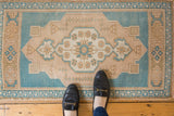 Aqua blue and sand floral motif within scalloped medallion of distressed vintage Oushak rug.