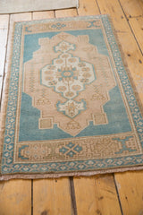 Distressed Oushak rug corner, aqua green blue border and sand floral motifs, even wear.