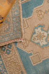 Distressed Oushak rug's hand-knotted foundation, selvage, fringe, and worn aqua sand pile.