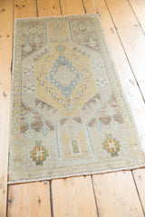 Distressed Oushak rug corner with softened sand, aqua geometric motifs and original fringe.