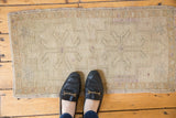 Vintage distressed Oushak rug mat showing primitive motifs, muted ivory, sand, and beige colors.