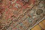 Distressed Heriz rug detail: faded geometric palmettes, contrasting blue border patterns, and worn pile.